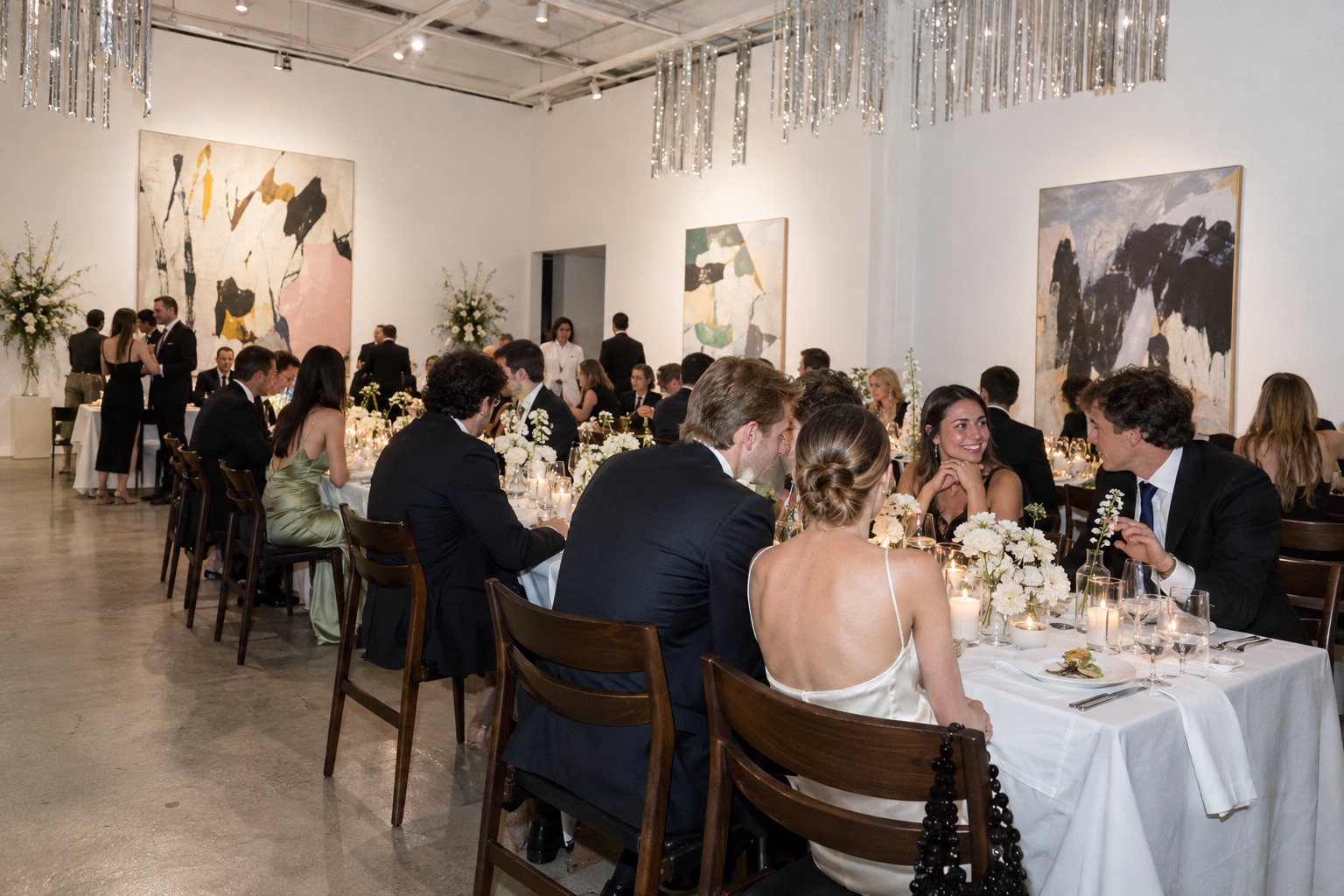 Source-grounded editorial illustration of long white-clothed wedding tables in a contemporary art gallery
